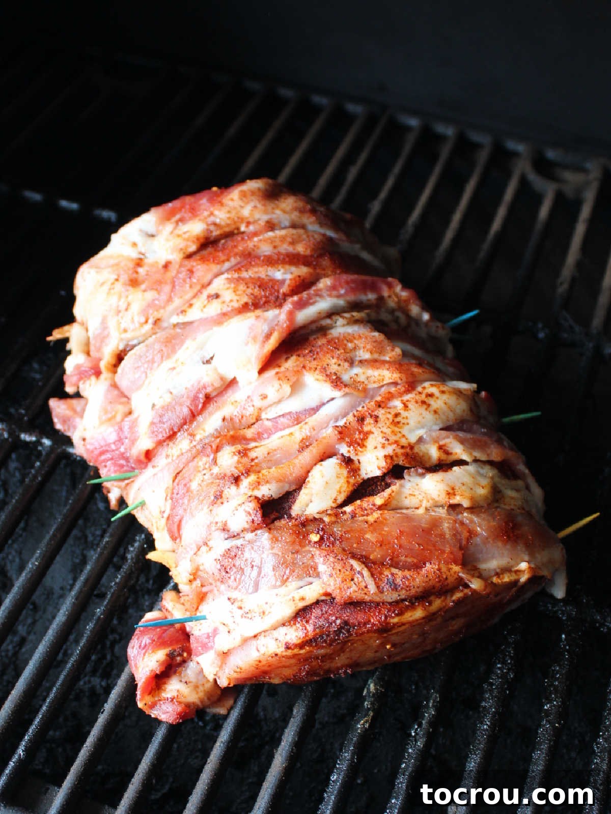 Bacon wrapped pork loin right after it was placed on smoker grates.