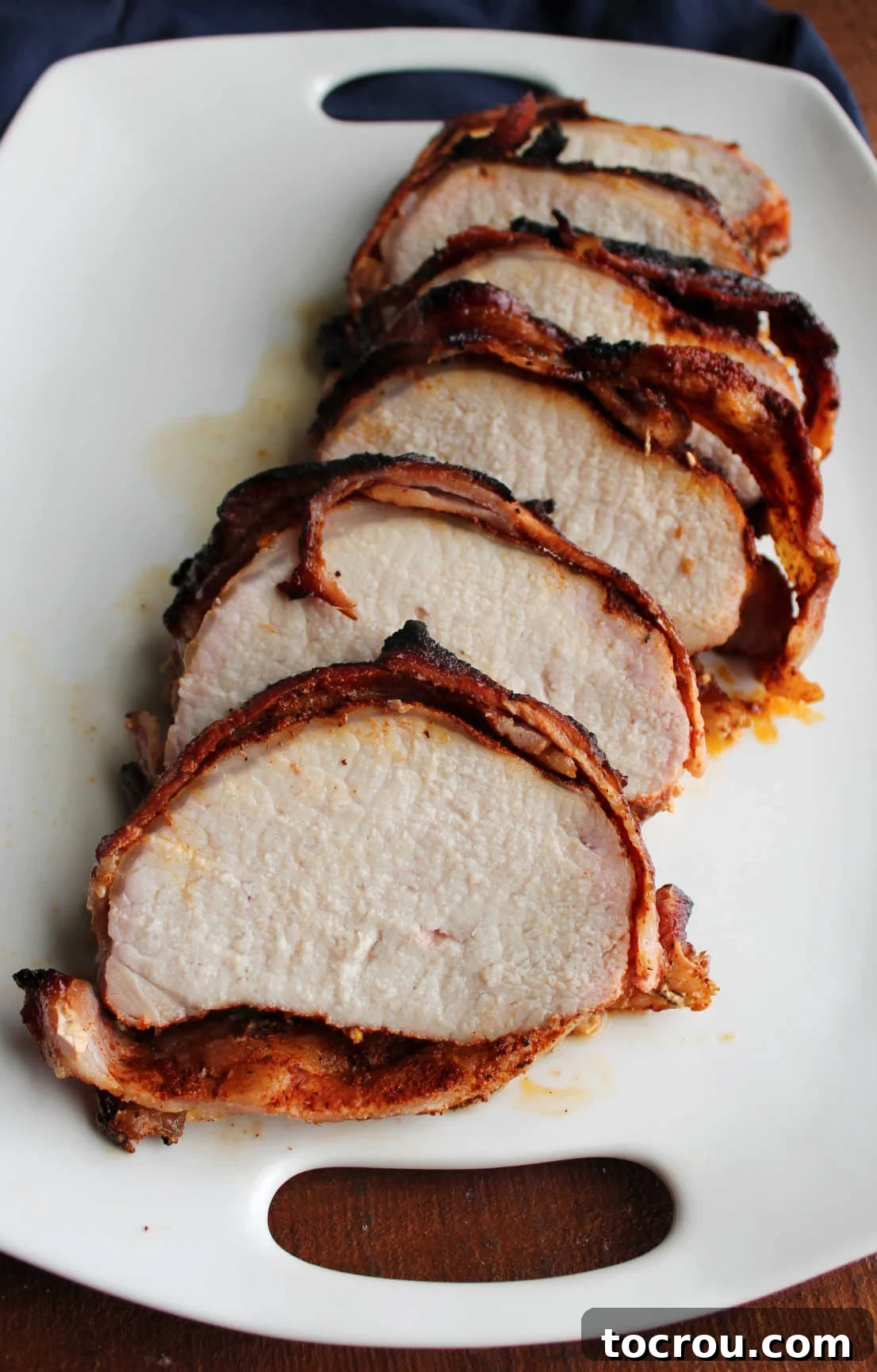 Slices of bacon wrapped pork loin on platter, ready to be served.