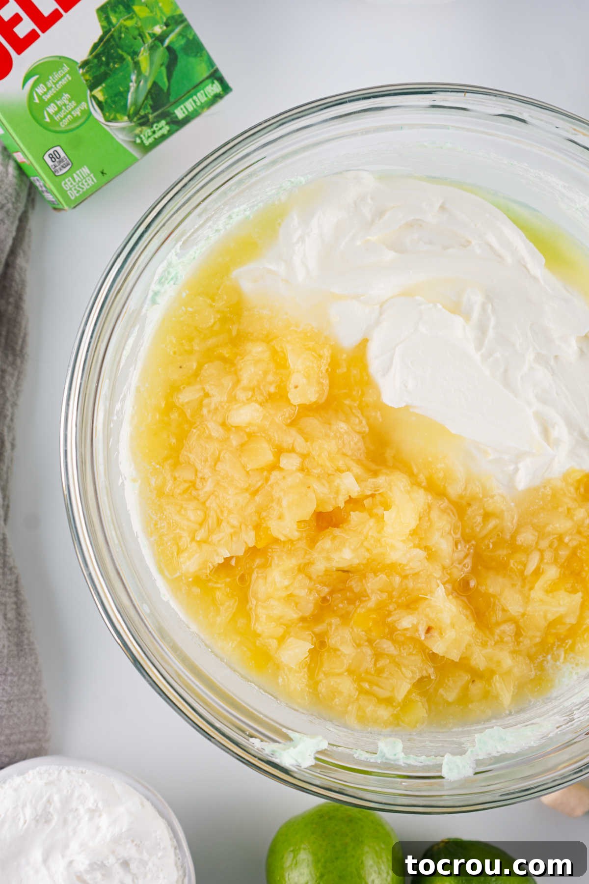 Adding crushed pineapple and sour cream to the lime cool whip mixture.