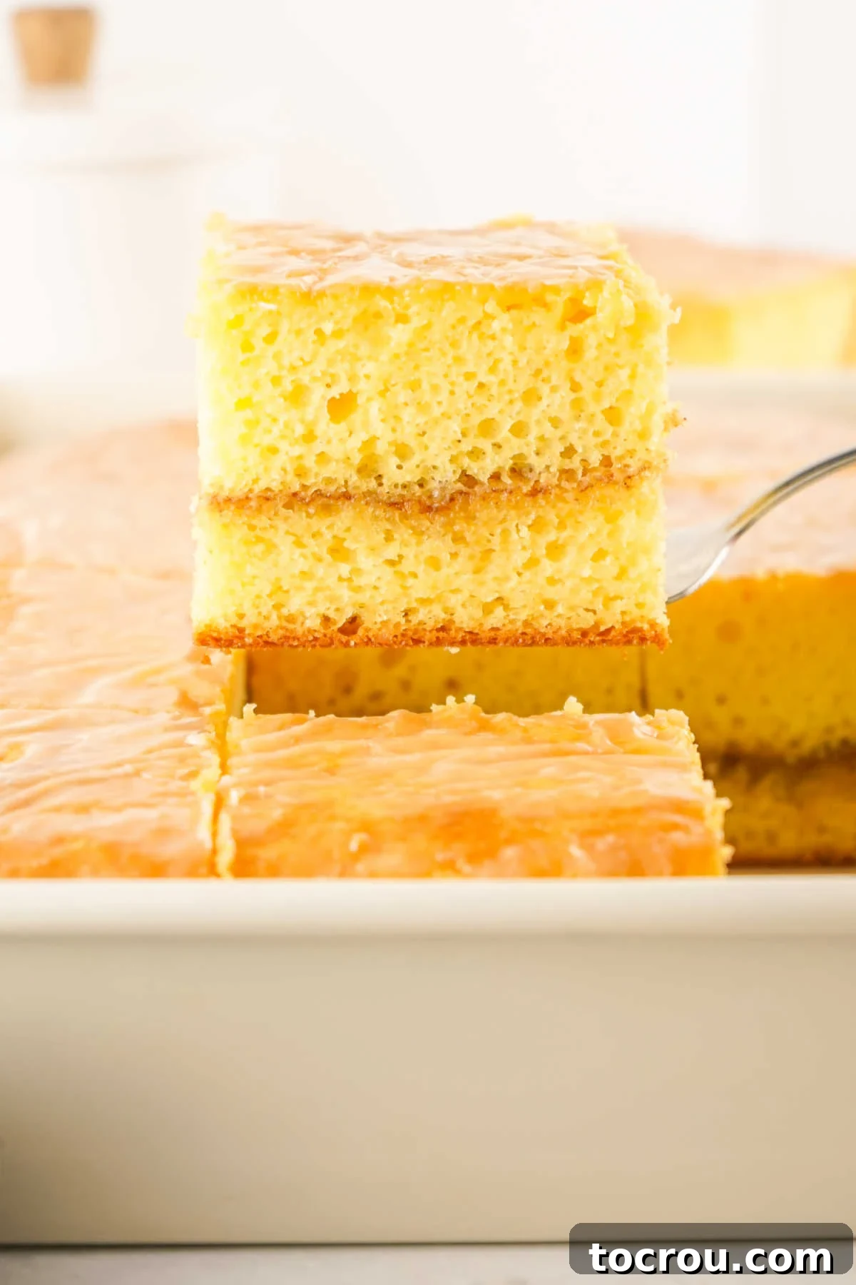 Lifting a piece of honey bun cake out of the pan, clearly showing the distinct layer of cinnamon and brown sugar baked into the middle.