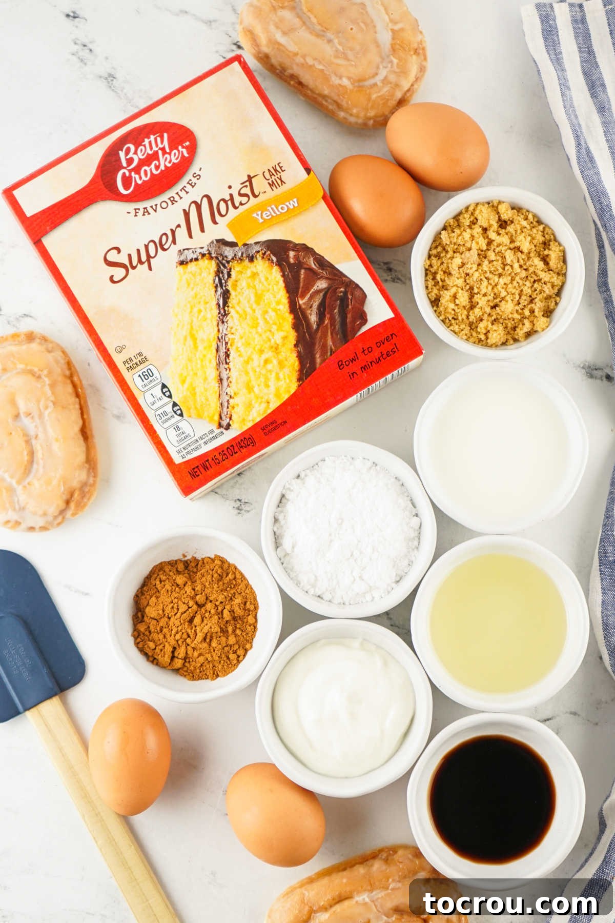 Ingredients for homemade honey bun cake, including a yellow cake mix, eggs, vegetable oil, vanilla extract, powdered sugar, brown sugar, cinnamon, and milk, laid out and ready for preparation.