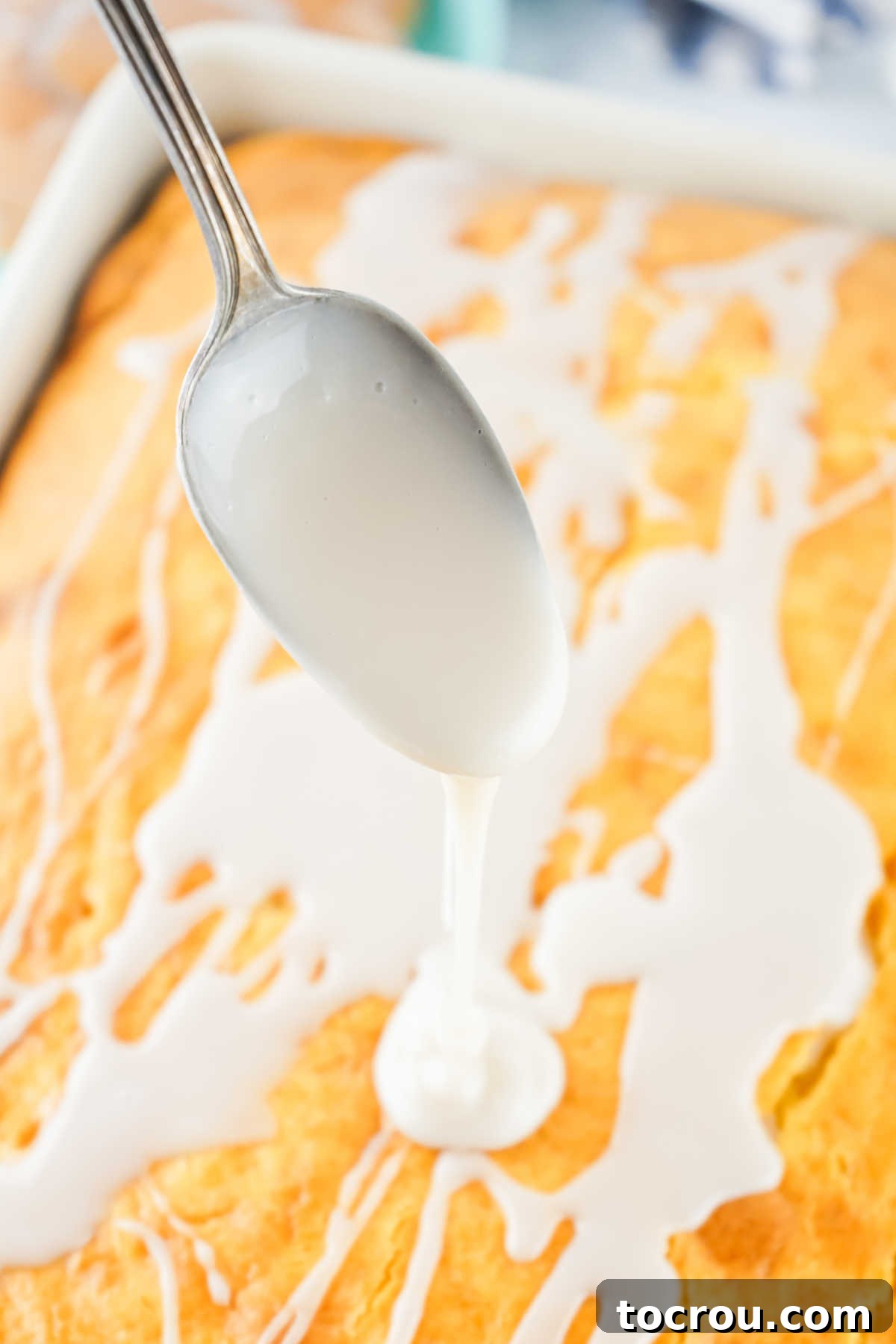 Drizzling white powdered sugar glaze over a warm, freshly baked honey bun cake in a 9x13 inch pan.