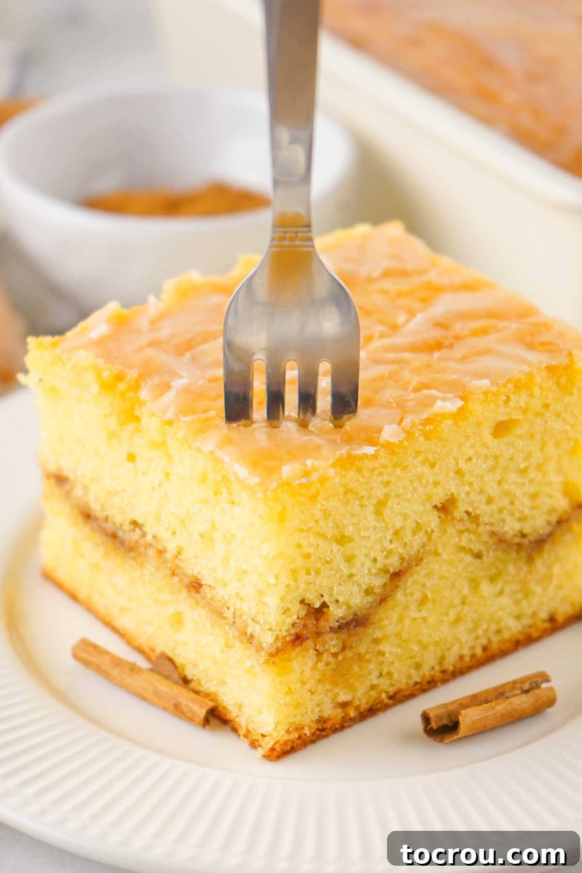 Fork going into moist vanilla cake with a delicious cinnamon sugar ribbon in the center, highlighting the layers.