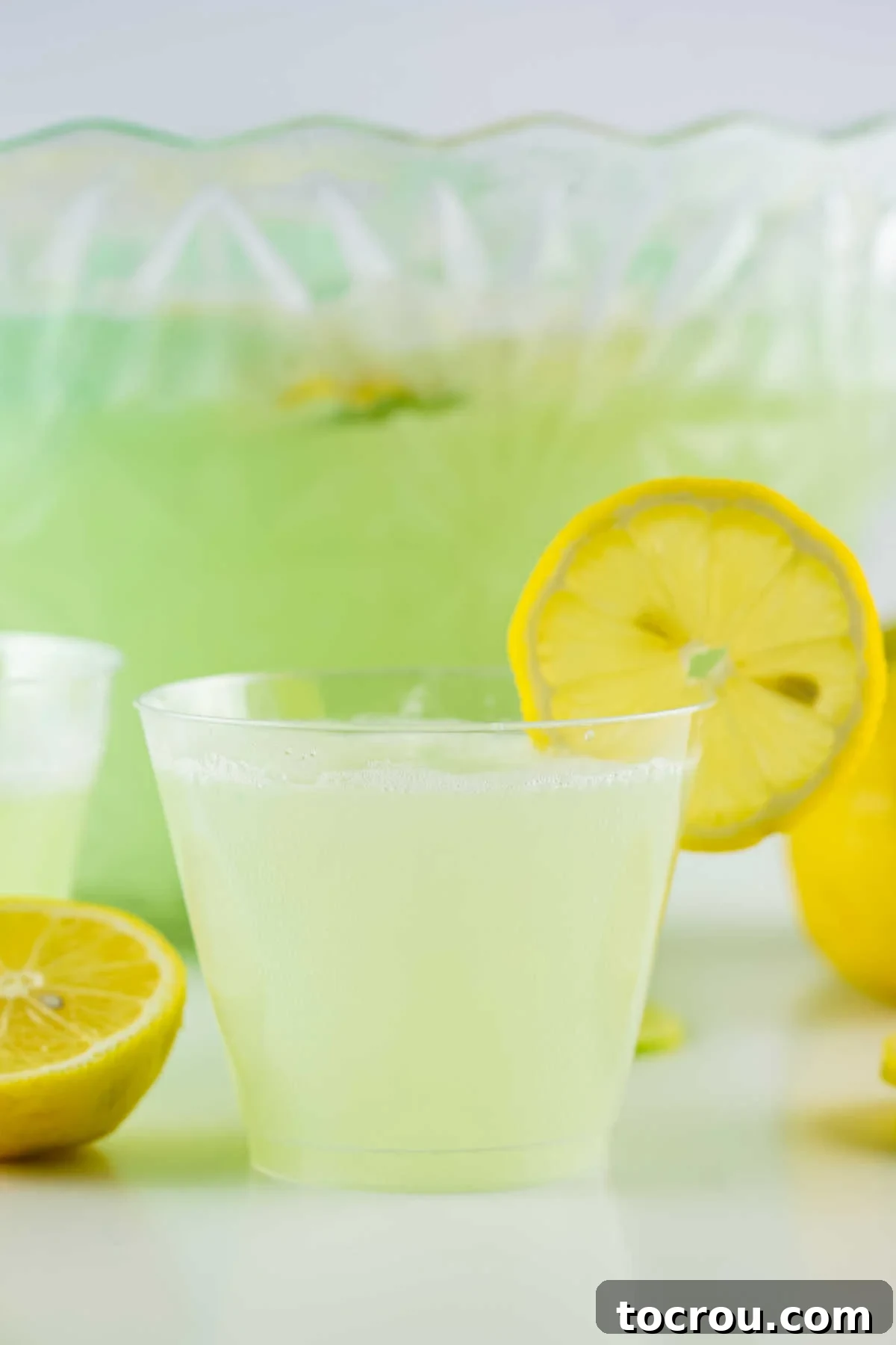 Glass of lemon lime sherbet punch garnished with a slice of lemon, ready to drink.
