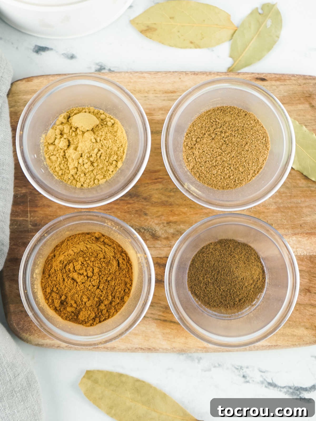 Small jars of spice powders ready to be combined to make homemade pumpkin pie spice. 