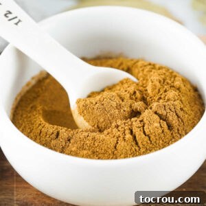 Small bowl filled with homemade pumpkin pie spice and a measuring spoon, ready to be used.