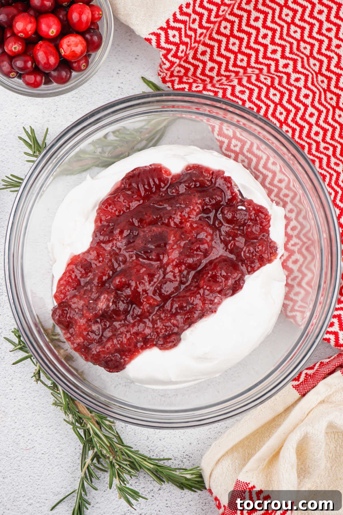 Ruby Cranberry Infusion Cake 6 Mixing bowl with cool whip and whole cranberry sauce in it, ready to be stirred together to make a simple frosting.