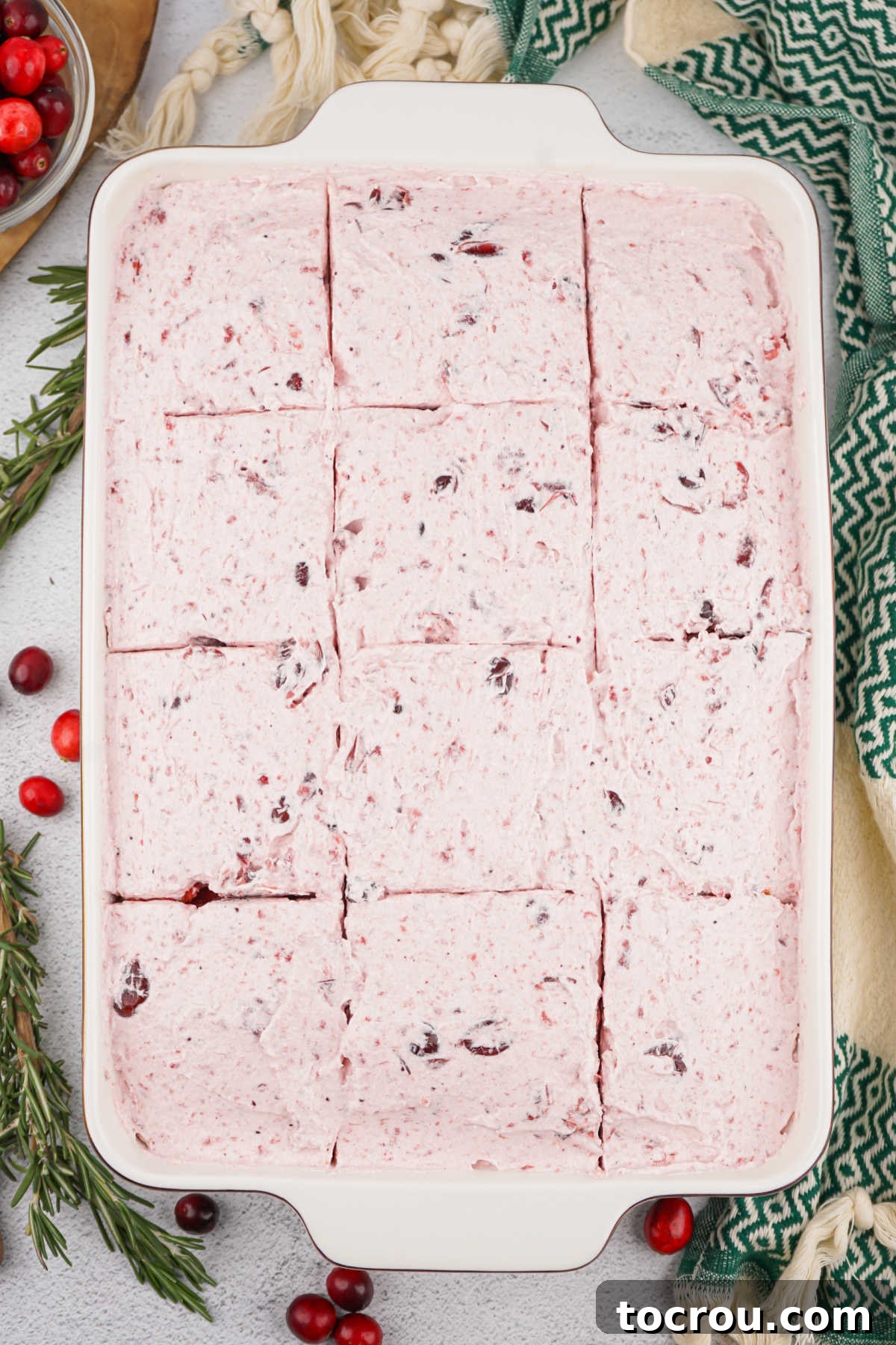 Ruby Cranberry Infusion Cake 7 Cake topped with cranberry and cool whip frosting, cut into squares, ready to serve.