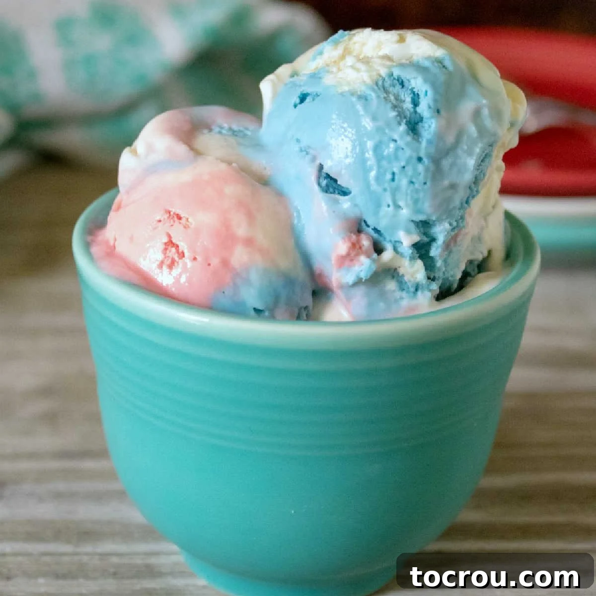 Patriotic Swirl No-Churn Delight 2 A blue mug filled with scoops of vibrant red, white, and blue swirled ice cream, ready to be enjoyed.
