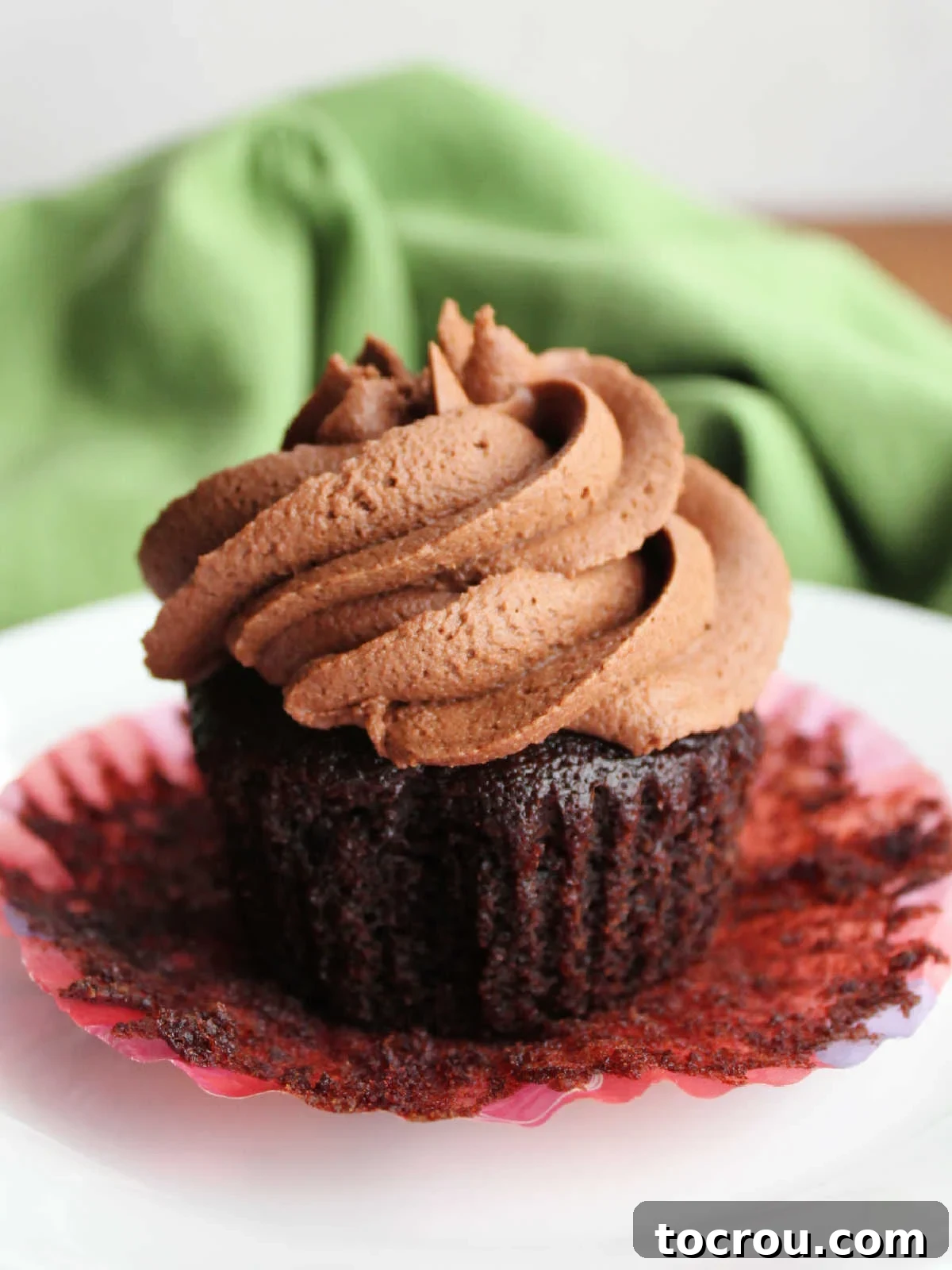 Crazy Delicious Chocolate Cupcakes 8 Chocolate cupcake with the wrapper pulled down and a swirl of chocolate buttercream frosting on top.