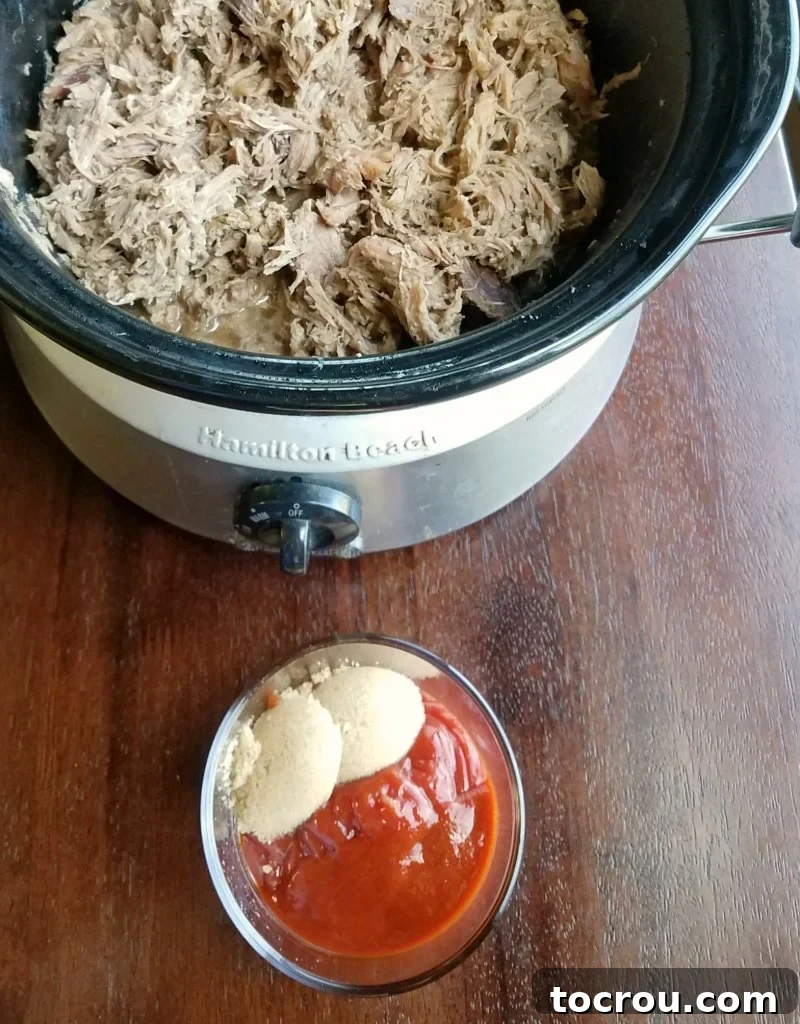 Slow cooker filled with pork shoulder, with a bowl of ingredients for the sriracha sauce alongside it.
