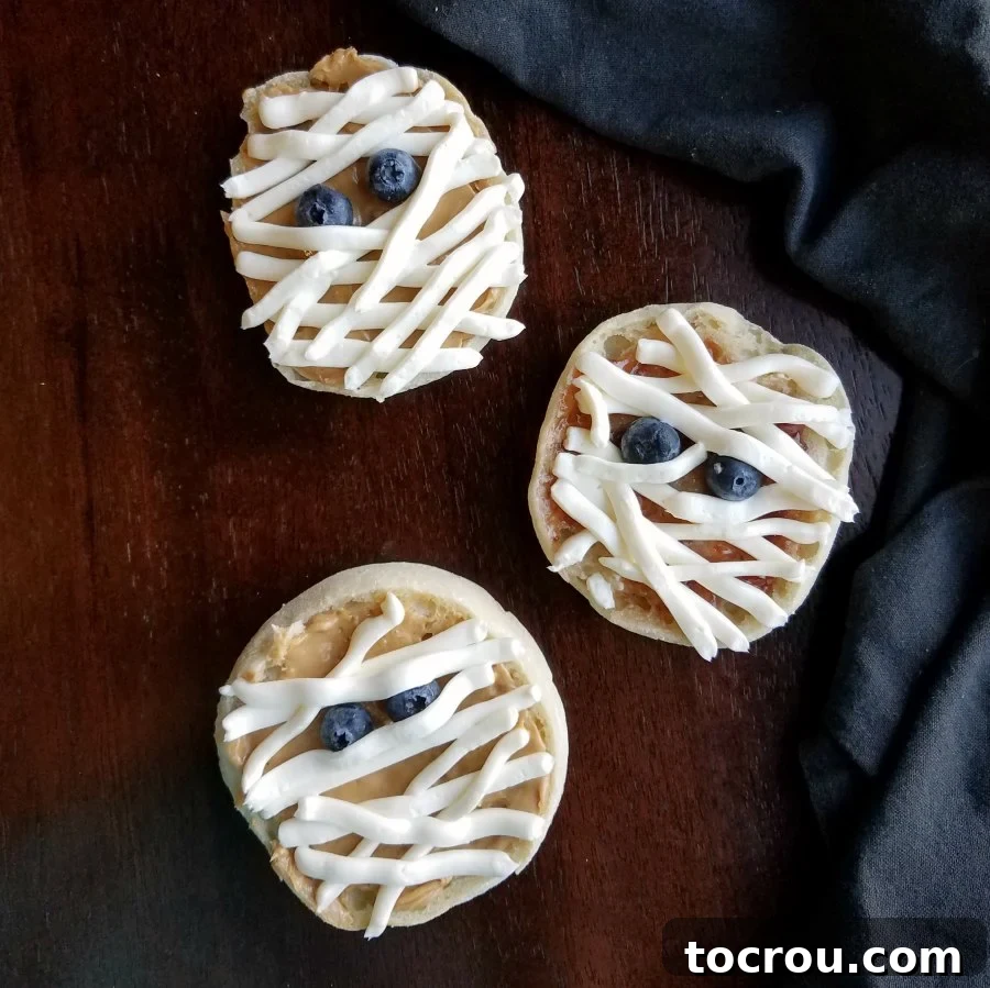 Easy English Muffin Mummies: A Quick and Fun Halloween Breakfast Treat Adorable English muffin mummies with cream cheese bandages and blueberry eyes, ready for a Halloween breakfast.