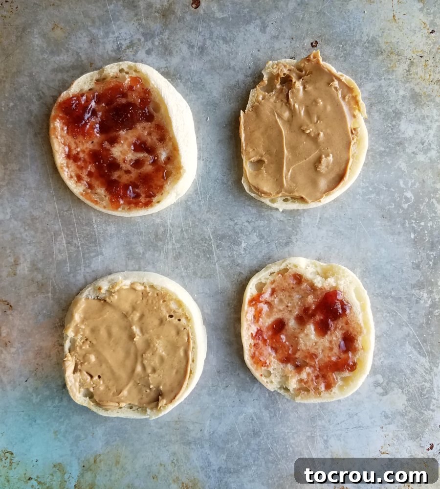 Simple Spreads for Halloween Mummy English Muffins English muffin halves spread with creamy peanut butter or sweet jelly, ready for the next step of mummy creation.