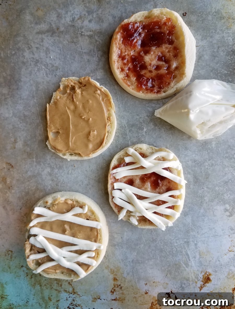 Piping Cream Cheese Bandages for English Muffin Mummies A plastic baggie filled with cream cheese mixture, being piped into mummy-like bandages over an English muffin.