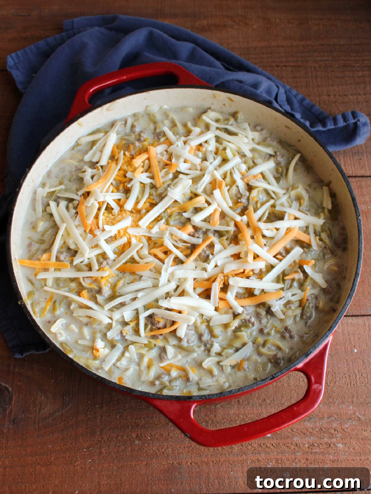 A sprinkling of shredded cheddar cheese over the pan of cooked hot dish.