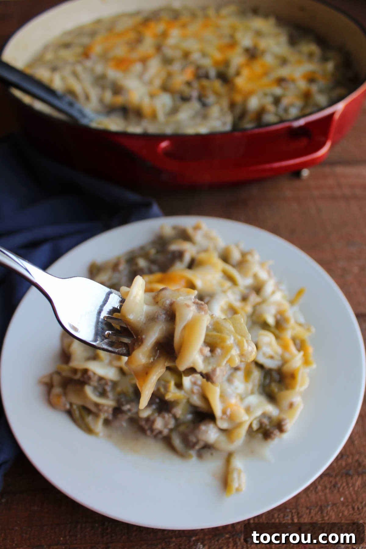 Bite of one pot hot dish on fork showing creamy texture and cooked pasta with ground beef and green beans.