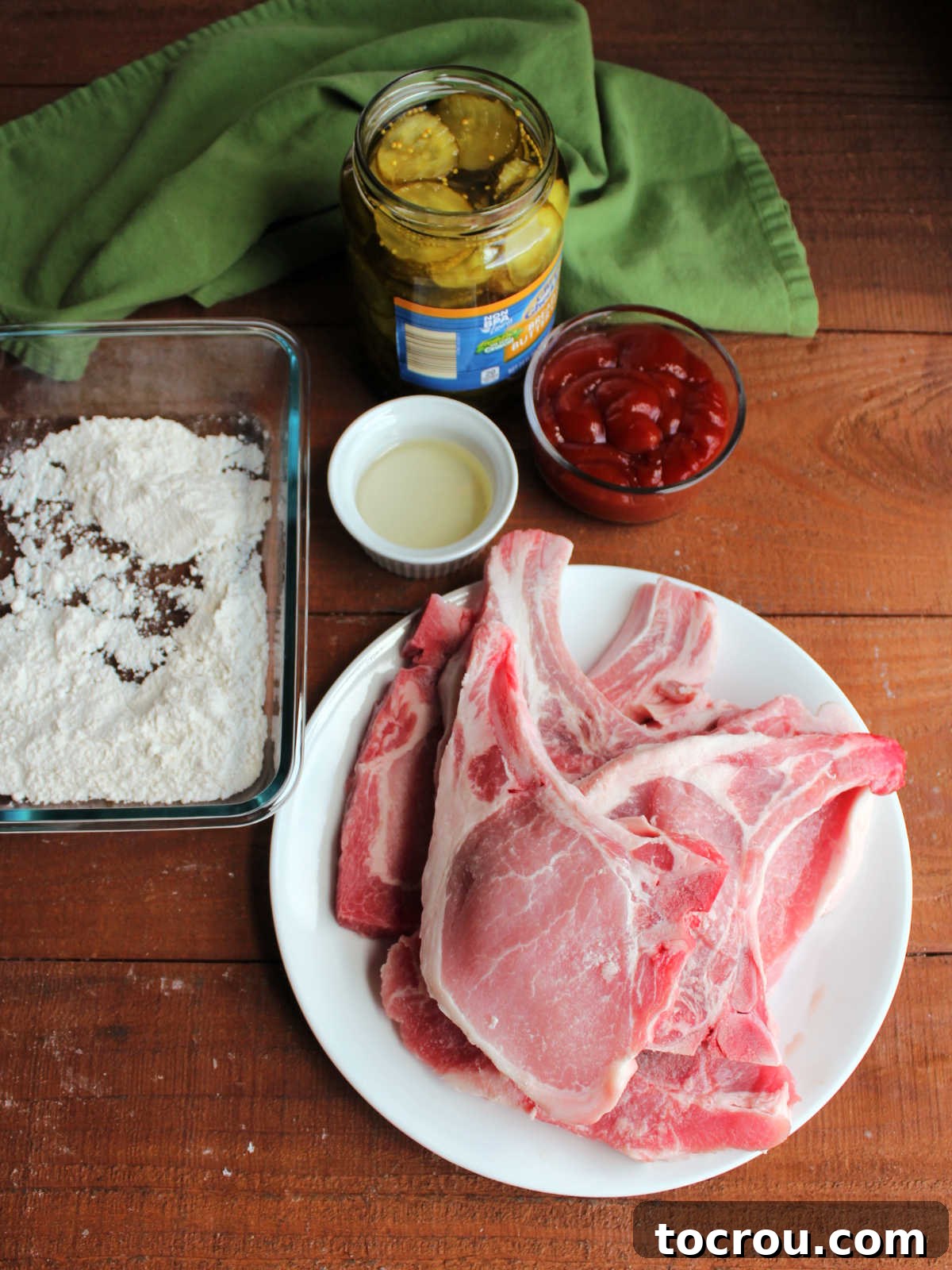 Ingredients including bone in pork chops, flour, oil, ketchup and bread and butter pickles. 