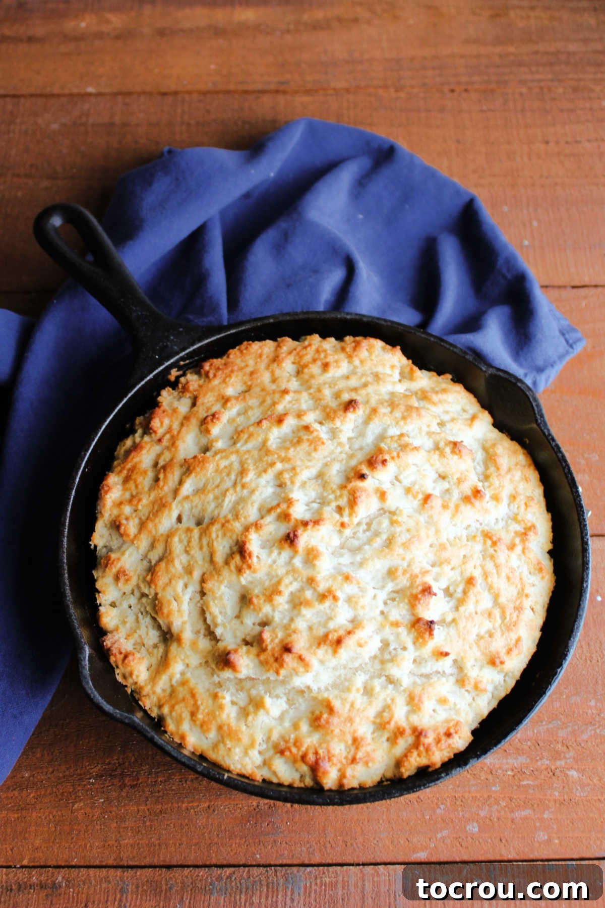 Cast iron with baked pone bread in it fresh from the oven, showing golden brown crust on top.