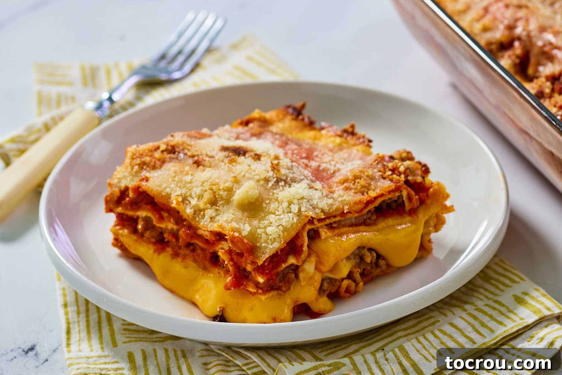 Maw-Maw's Cheesy Velveeta Lasagna A perfectly portioned slice of golden-brown Velveeta lasagna, showcasing its layers of rich red sauce, savory ground beef, melted mozzarella, and the signature gooey Velveeta cheese. It sits ready to be enjoyed, promising ultimate comfort with every forkful.
