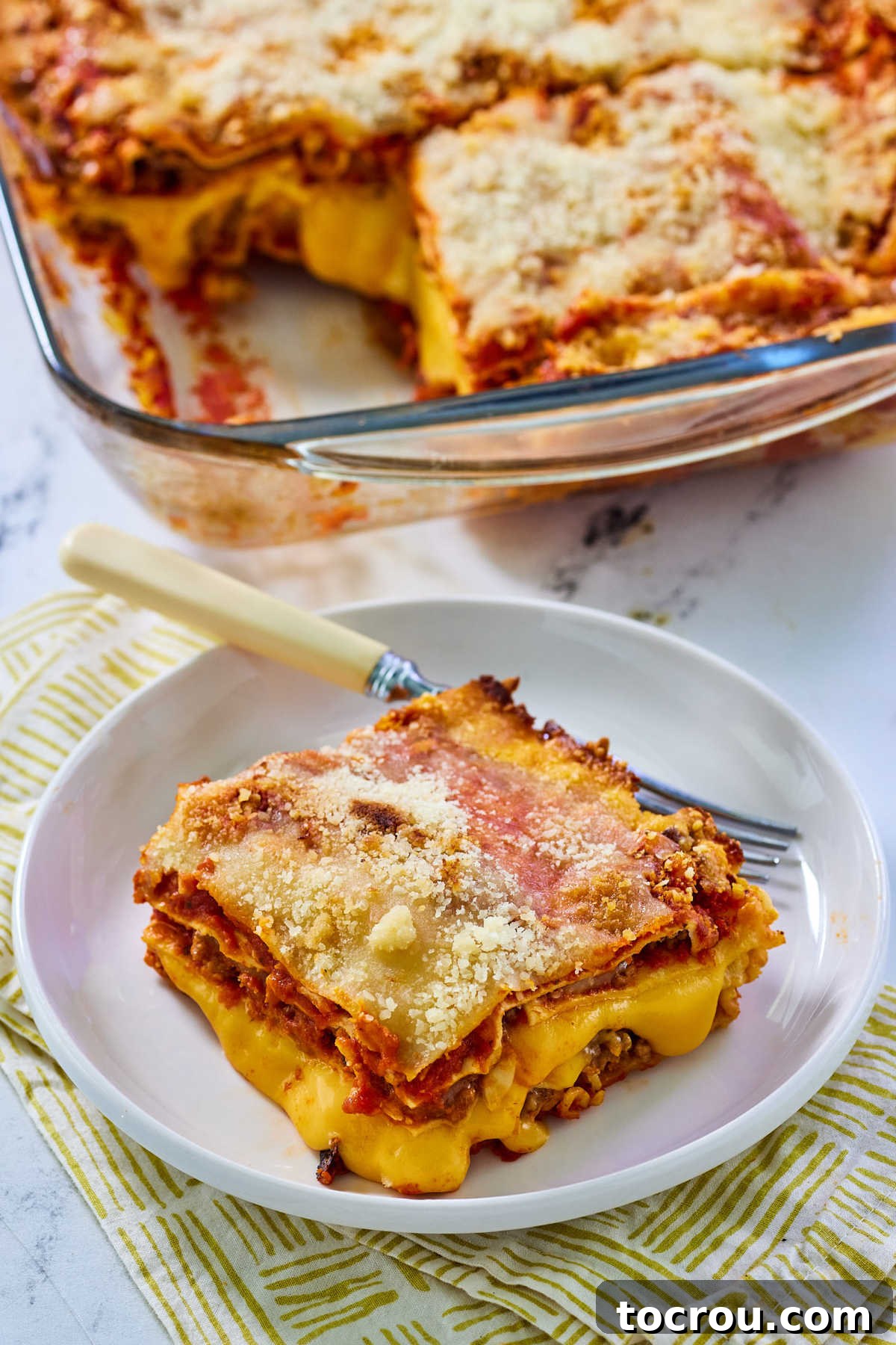 Melty Velveeta Cheese in Lasagna A close-up view of a serving of Velveeta lasagna, revealing the signature smooth, golden Velveeta cheese oozing delightfully between layers of pasta, meat, and sauce. The rich texture is evident, promising a mouthful of cheesy goodness that's unique to this recipe.