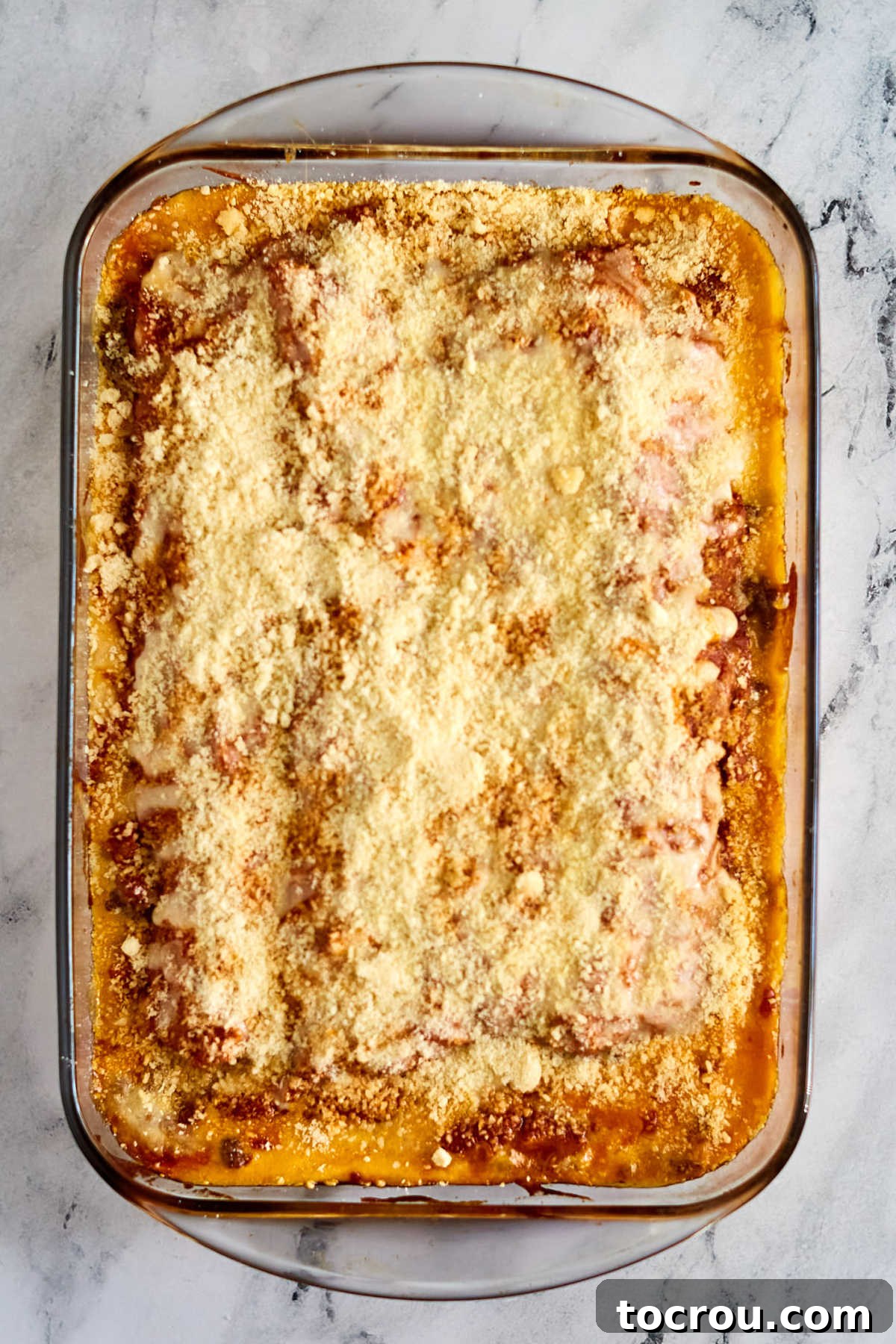 Baked Ground Beef and Velveeta Lasagna A golden-brown baked lasagna fresh from the oven, showing its beautifully melted and slightly crisped mozzarella and Parmesan topping, with bubbling red sauce peeking through. The edges are perfectly browned, indicating a delicious crust and a perfectly cooked dish.
