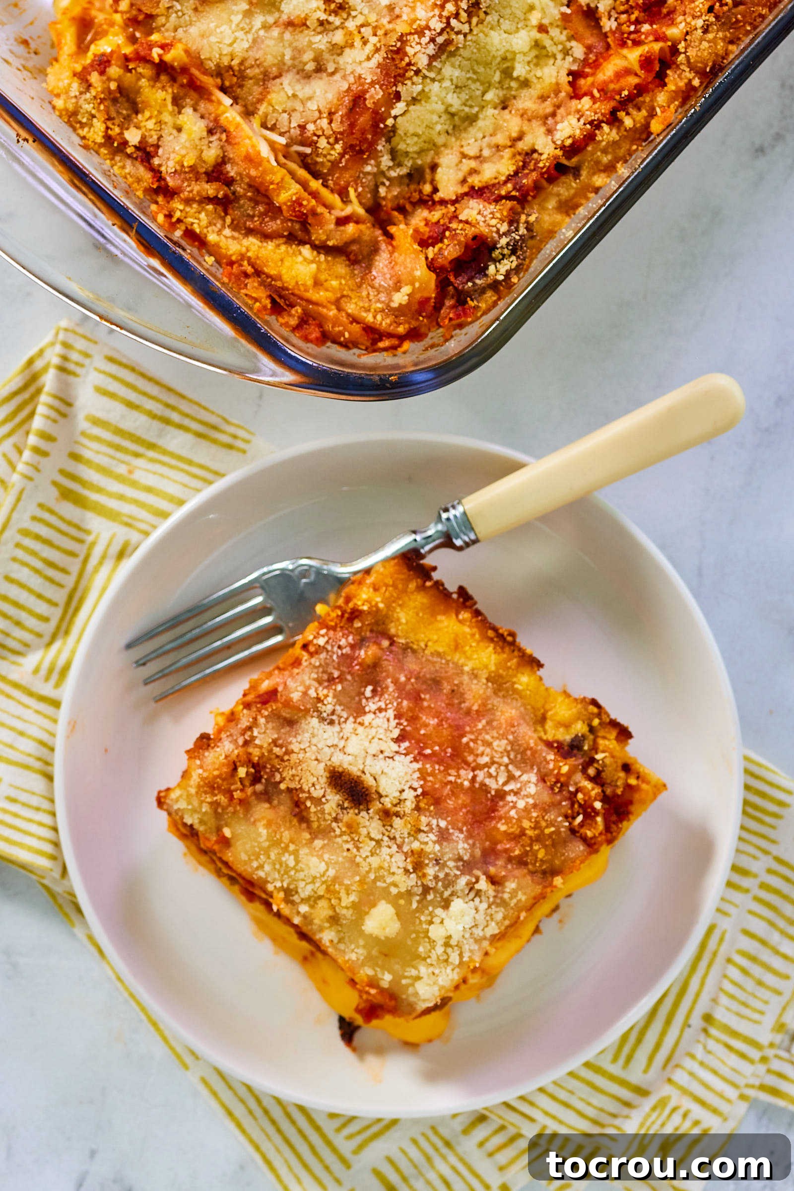 Perfectly Baked Lasagna Slice An inviting overhead close-up of a generous serving of lasagna, showcasing the rich tomato sauce and a perfectly golden-brown, bubbly cheese topping. The textures are clearly visible, promising a truly satisfying meal that is both hearty and comforting.