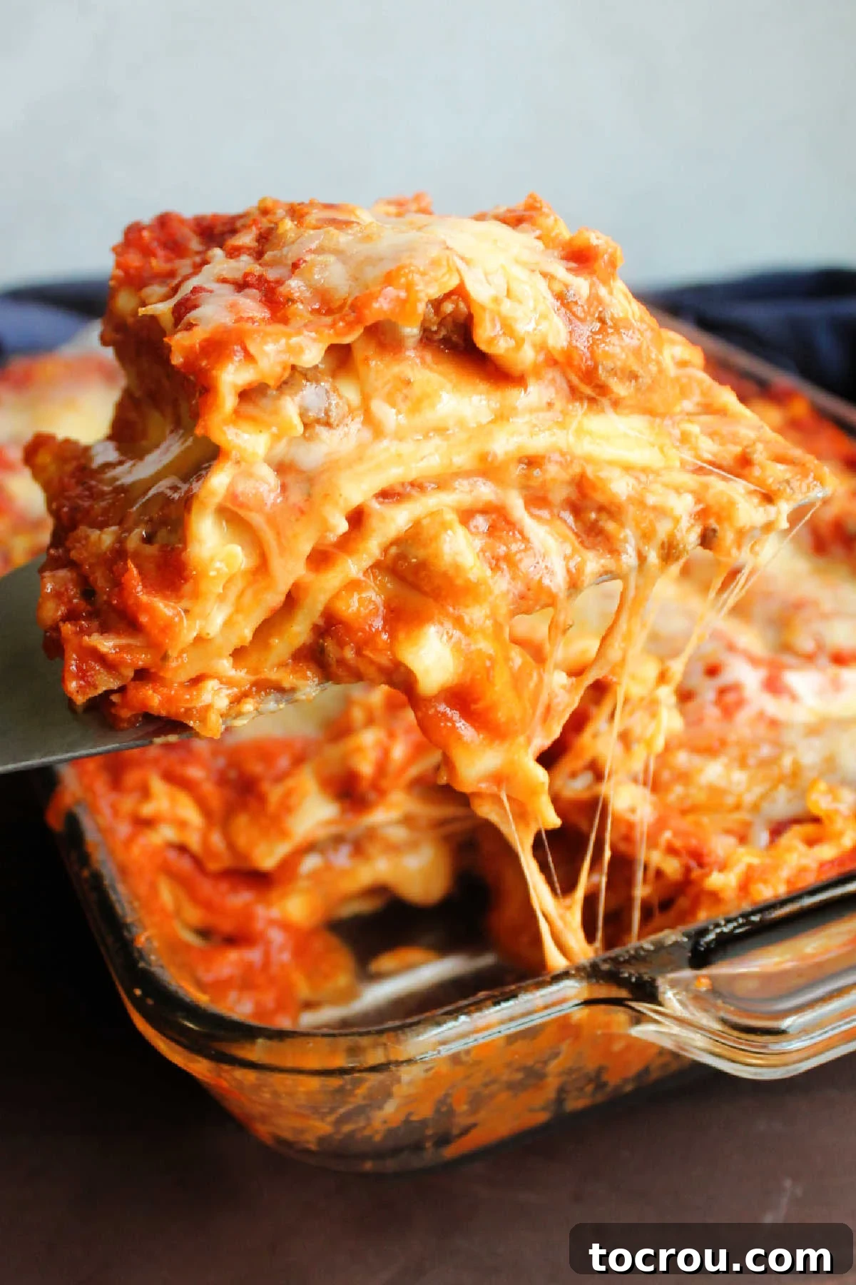 Serving Gooey Velveeta Lasagna A server lifting a gooey, cheesy slice of Velveeta lasagna from the baking pan. The Velveeta layer stretches and melts beautifully, highlighting the irresistible texture of this comfort food and showing off its rich, golden appeal.