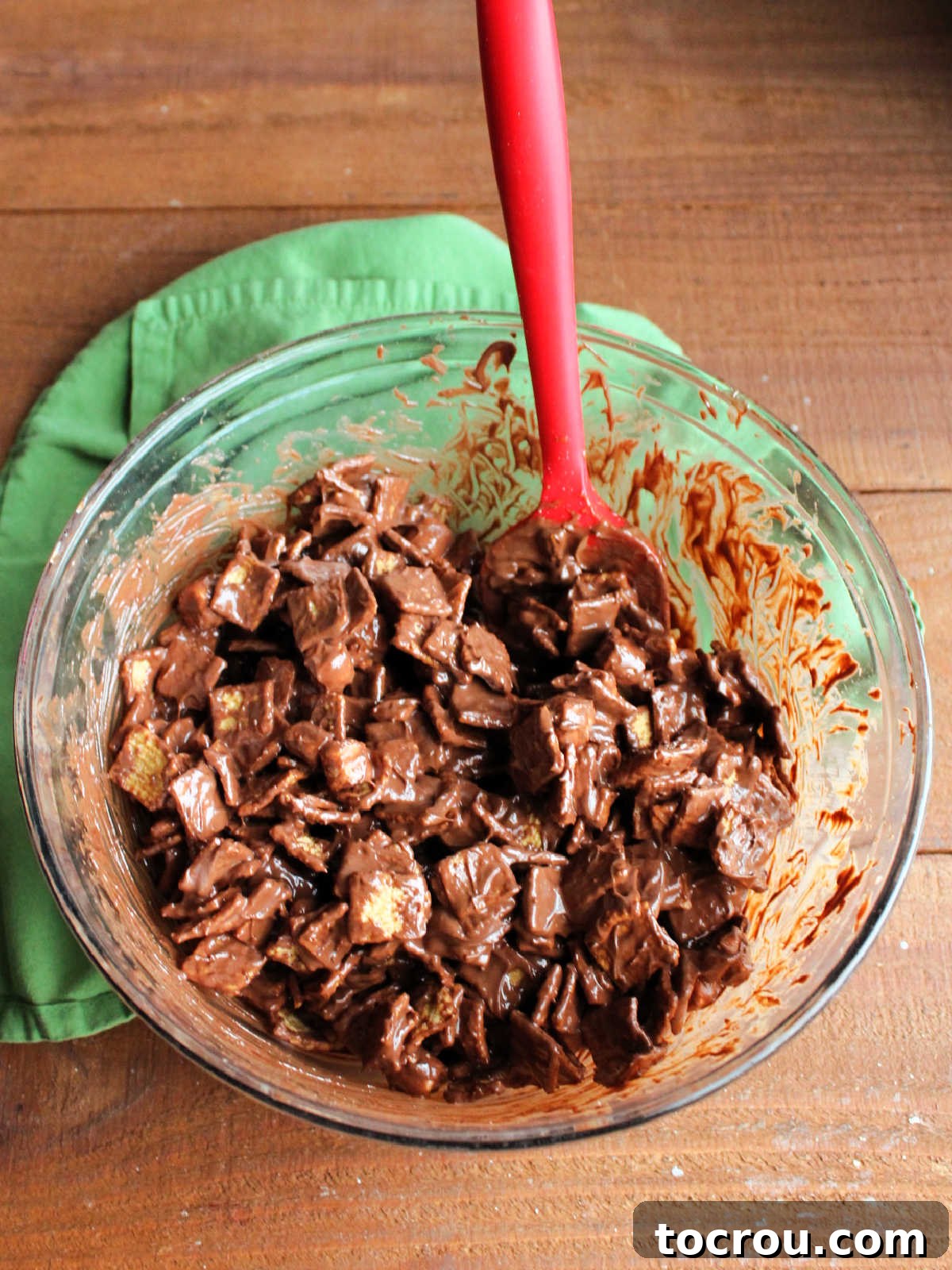 Mixing bowl with golden grahams cereal and some mini marshmallows coated in melted chocolate and peanut butter mixture.
