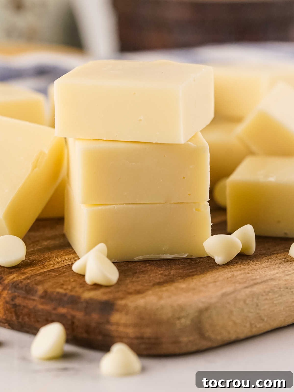 Three perfectly smooth pieces of vanilla fudge are stacked neatly, showcasing their consistent texture and inviting appearance.