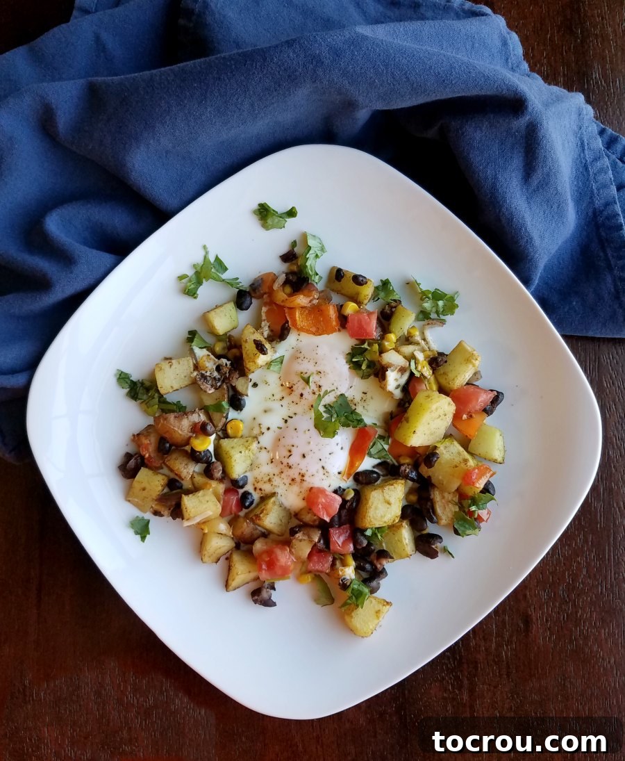 Simple to make but so full of flavor, this Tex-Mex sheet pan breakfast also makes a great dinner. Just chop the veggies and watch the magic happen! Plated filled with vegetables, eggs and sprinkled with cilantro and hot sauce.