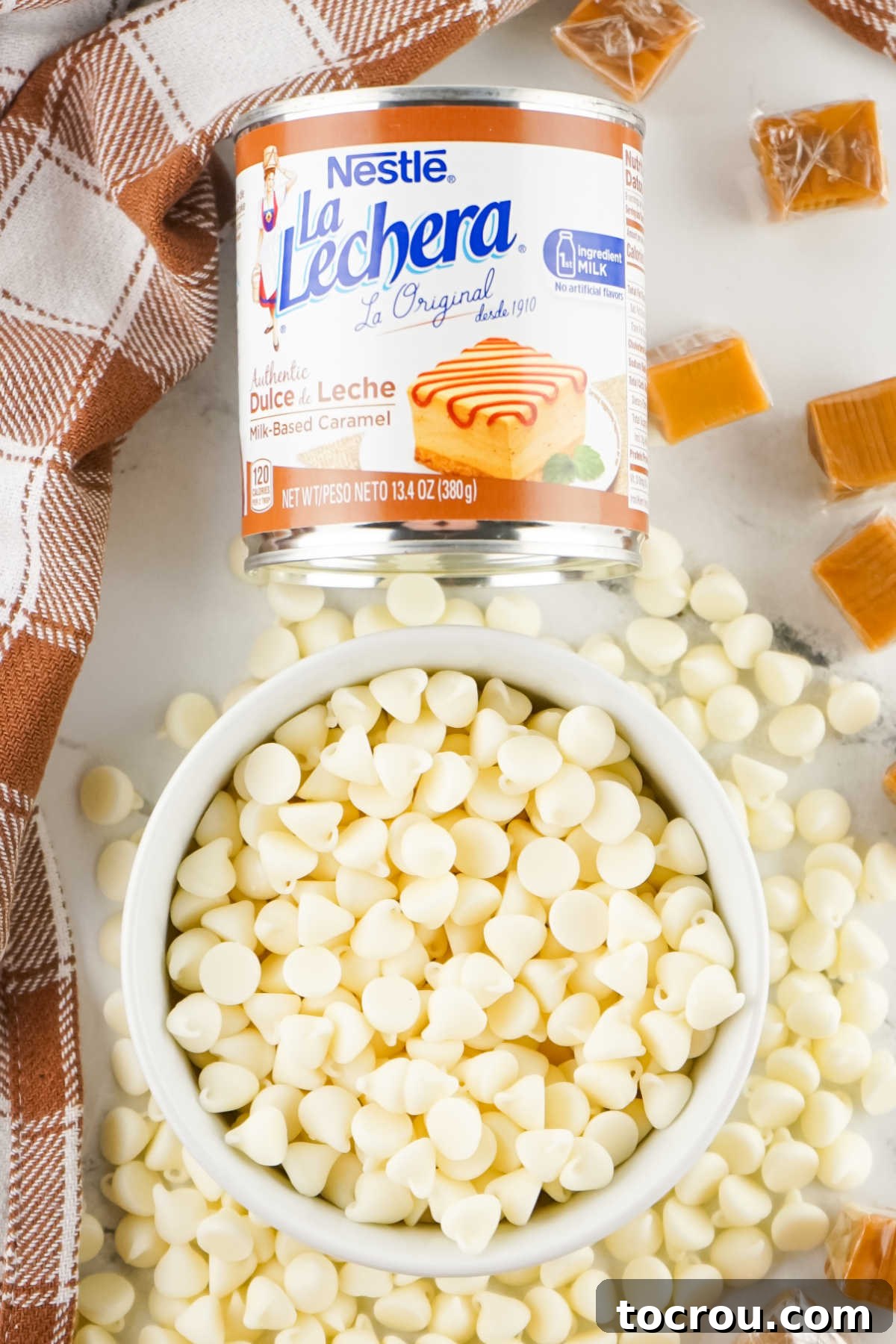 Ingredients for 2-Ingredient Caramel Fudge Bowl of white baking chips next to a can of Nestle Lechera dulce de leche, ready to be made into caramel fudge.