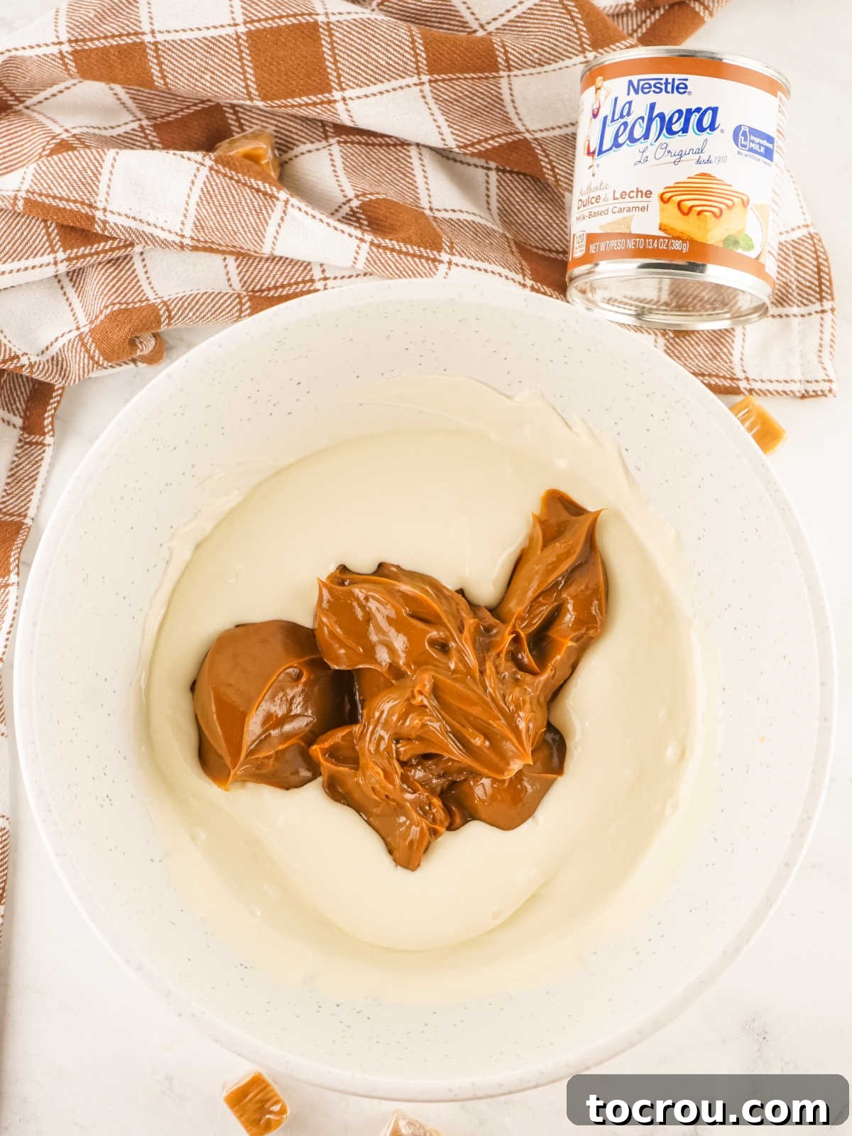 Mixing White Chocolate and Dulce de Leche Bowl of melted white chocolate chips with blob of dulce de leche in the middle, ready to be stirred together.