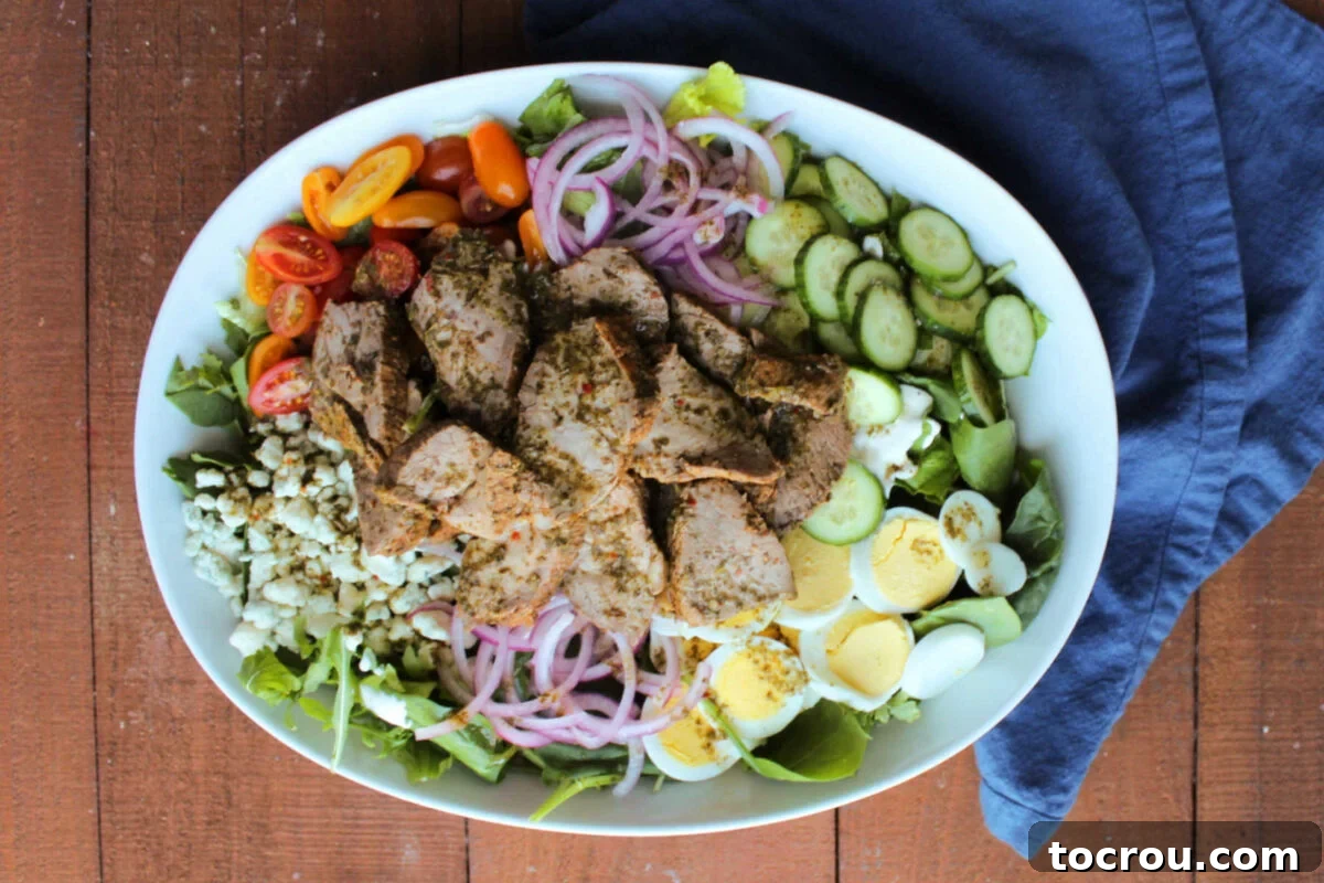 Fiercely Seared Rare Steak Salad 2 Oval serving bowl with black and blue steak salad topped with colorful vegetables, eggs, and a homemade creamy blue cheese dressing.