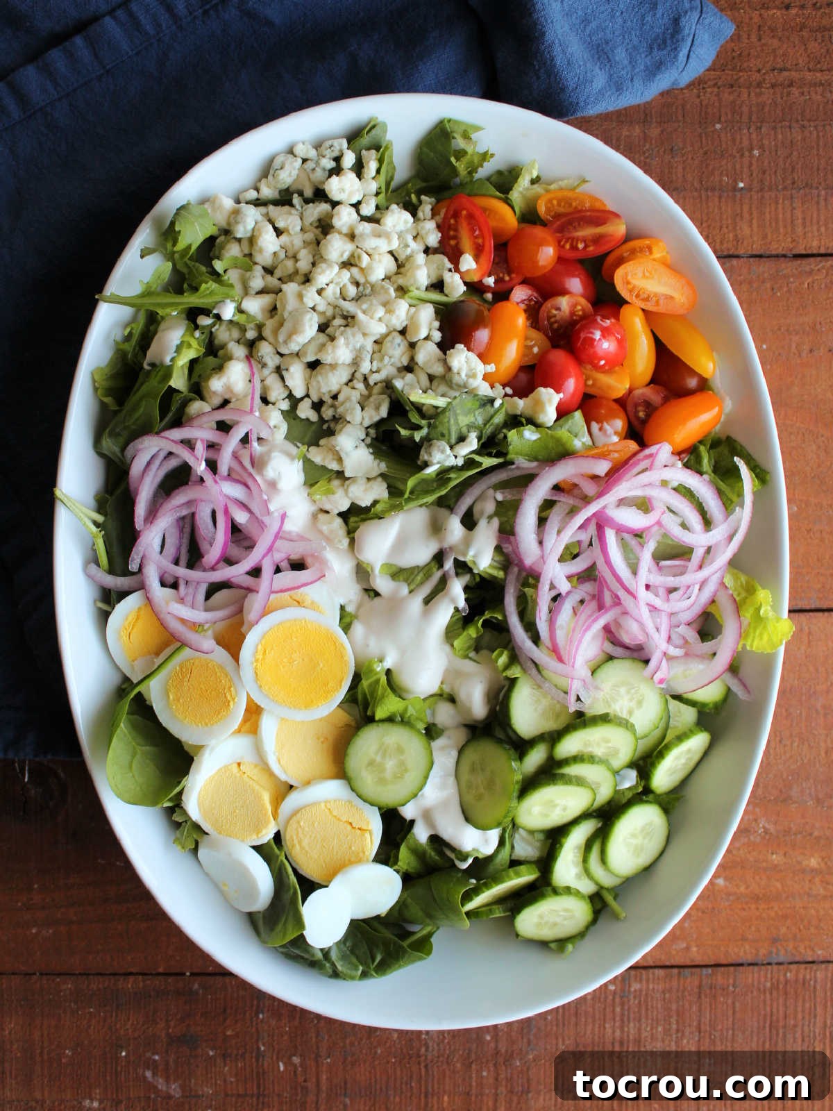 Fiercely Seared Rare Steak Salad 4 Salad topped with blue cheese dressing, hard boiled eggs, onion, tomatoes, cucumbers and blue cheese, ready for the steak.
