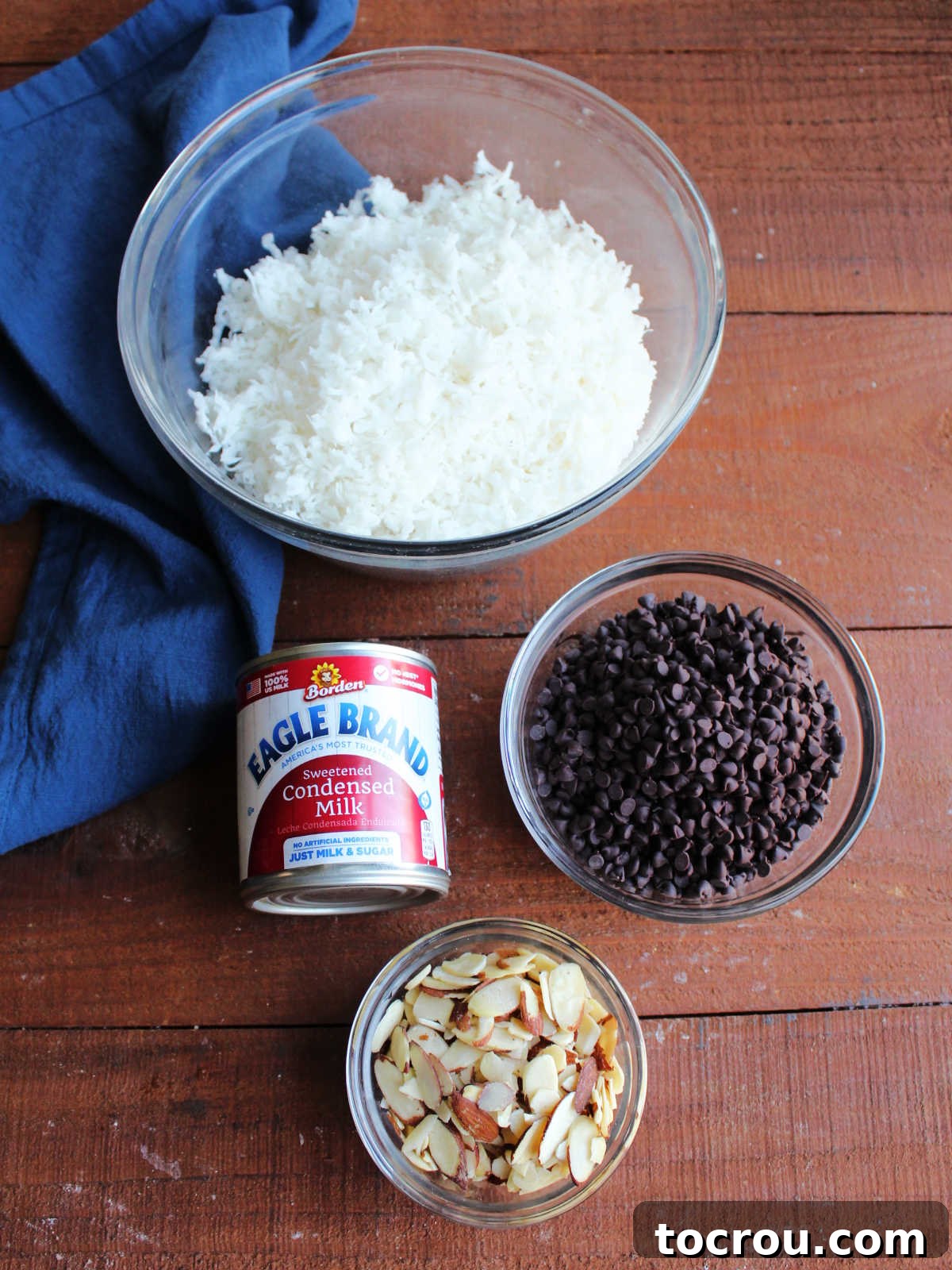 Maw-Maw's Delightful Almond Joy Macaroons 4 Ingredients including shredded coconut, sweetened condensed milk, mini chocolate chips, and sliced almonds ready to be made into macaroons.