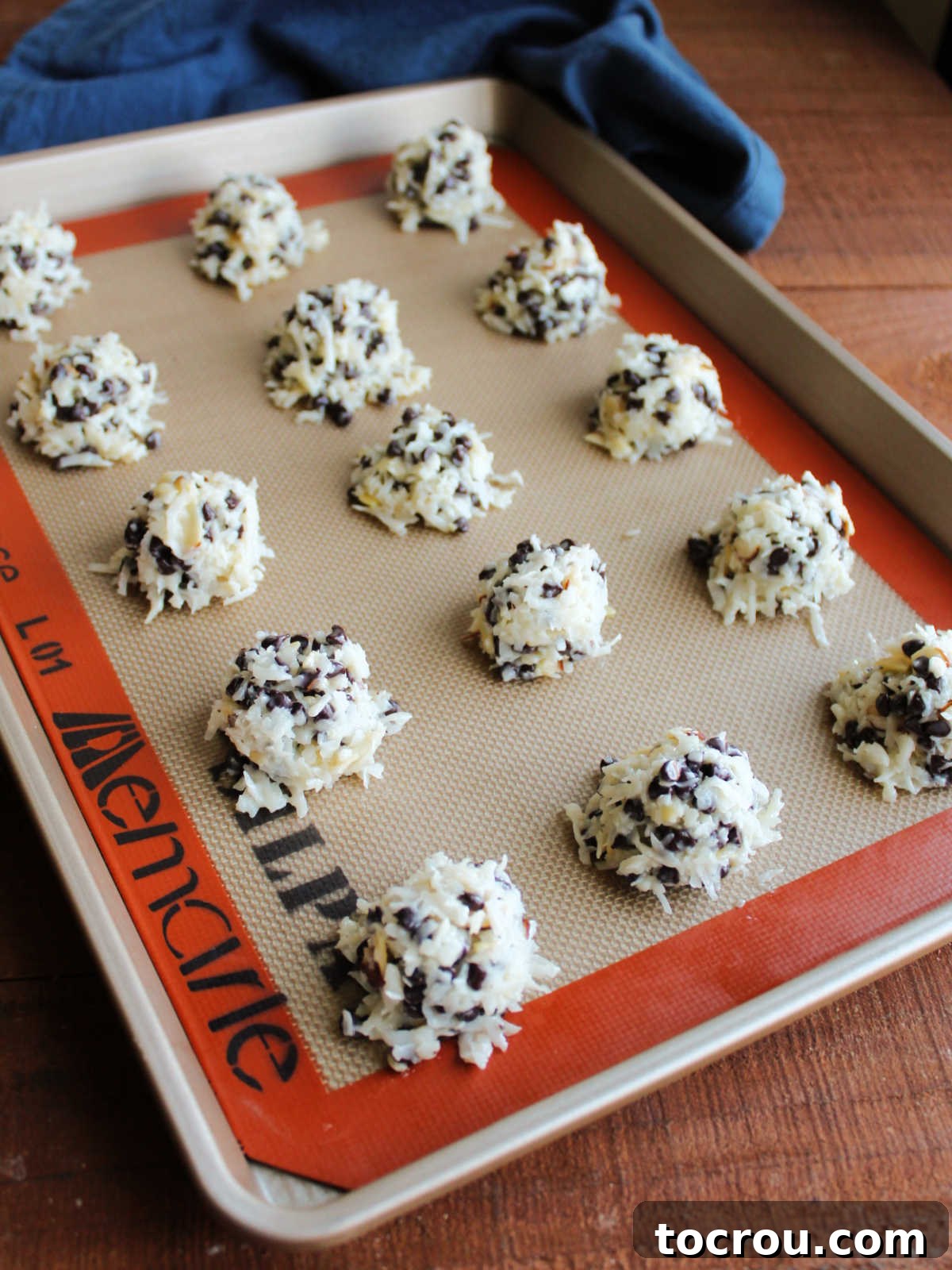 Maw-Maw's Delightful Almond Joy Macaroons 7 Scoops of the coconut mixture on a baking tray lined with a silicone mat, ready to go in the oven.
