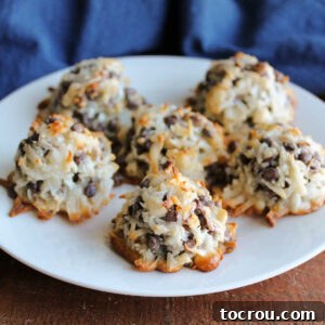 Maw-Maw's Delightful Almond Joy Macaroons 10 Plate with several almond joy macaroons on it showing toasted coconut, chocolate chips and bits of almonds in mounded cookie shapes.