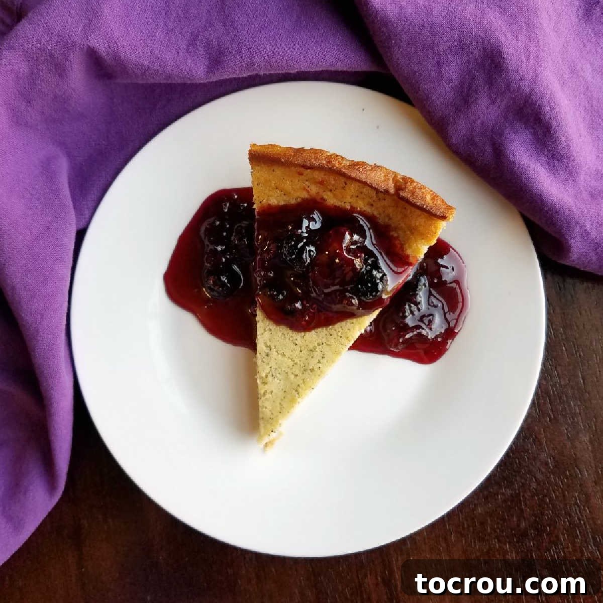 Enchanted Dragonfruit Pie 2 Piece of dragonfruit impossible pie topped with blackberry sauce on white plate.