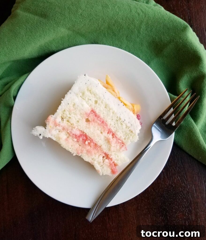 A slice of layer cake and a fork on a plate, ready to be enjoyed.