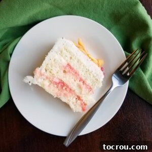 Slice of white cake with pink blood orange curd filling between layers.
