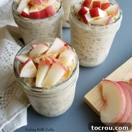 Jars of peaches and cream overnight oats topped with fresh peach chunks, a drizzle of honey, and a sprinkle of cinnamon.