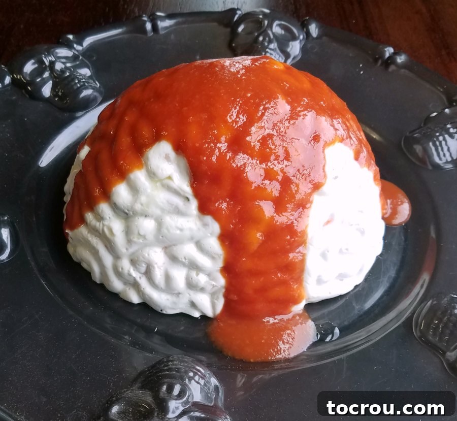 Close-up of brain-shaped shrimp spread with generous cocktail sauce blood poured over the top.
