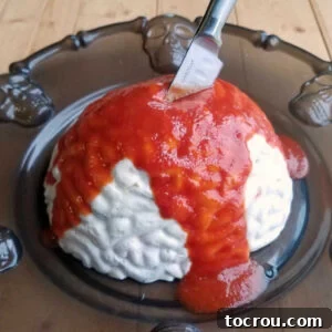 Brain-shaped shrimp spread with cocktail sauce blood poured over top and a knife sticking out.