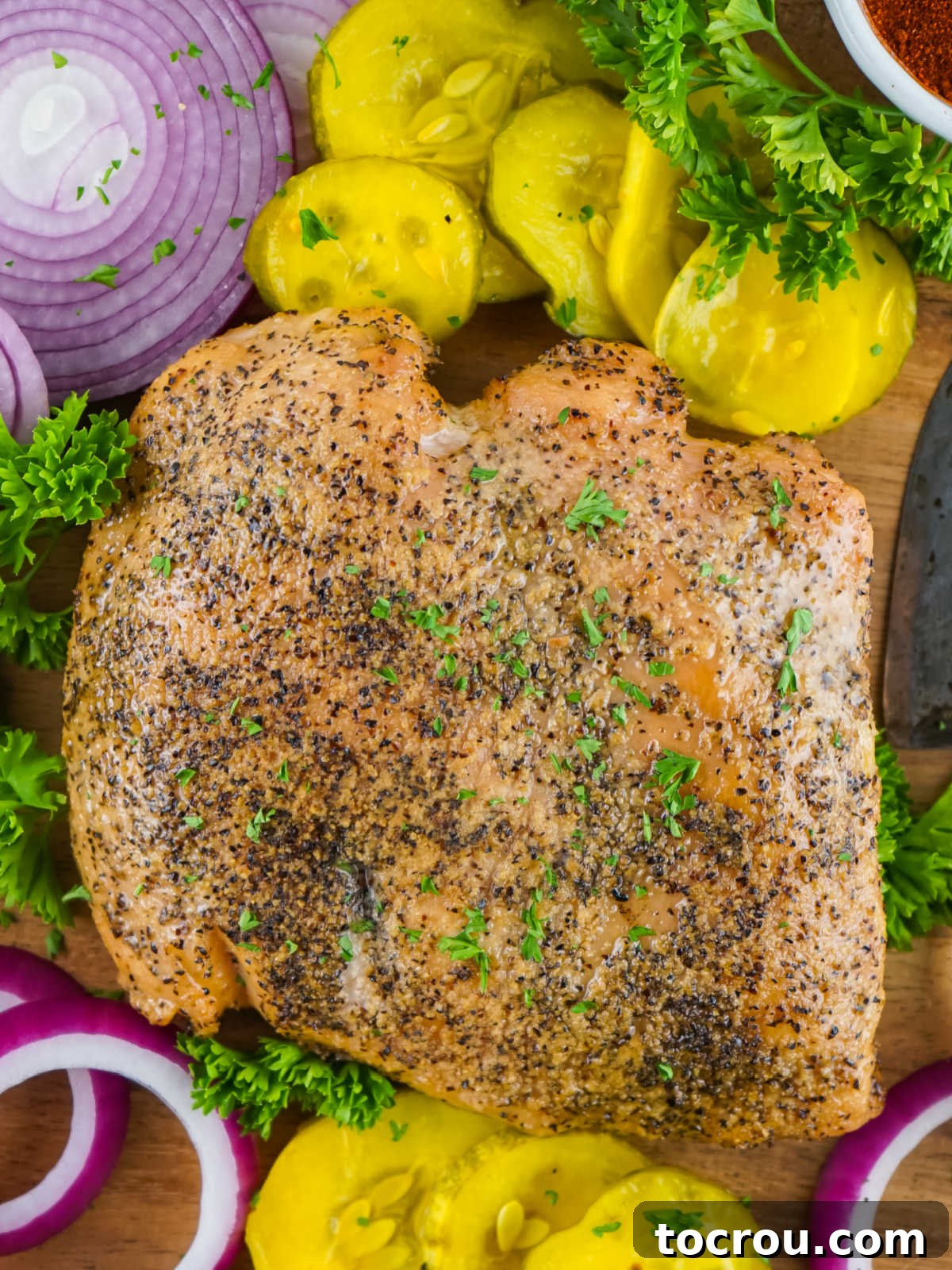 Gourmet Smoked Turkey Breast 4 A whole smoked turkey breast presented on a cutting board, garnished with bread and butter pickles and thinly sliced red onions.