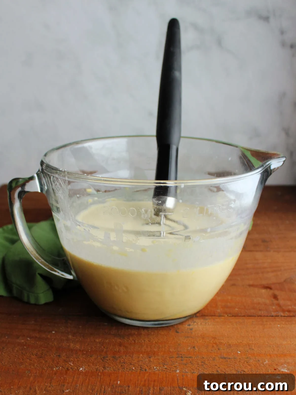 Mimi's Golden Custard Delight 4 Glass batter bowl with dutch baby batter and dough whisk inside.