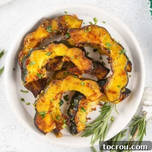 Plate of roasted acorn squash slices with herbs and parmesan cheese.