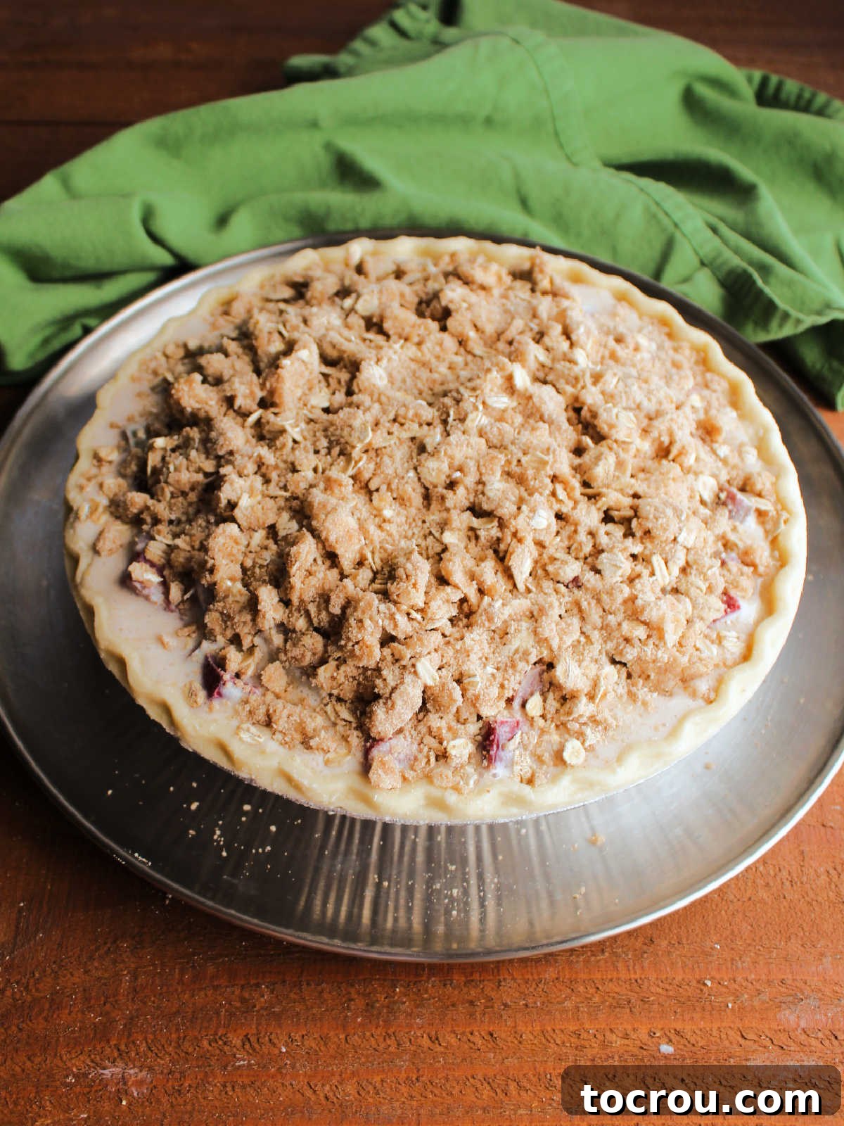 Buttery brown sugar and oat crumb topping over the rhubarb filling in the pie crust, ready to go in the oven.