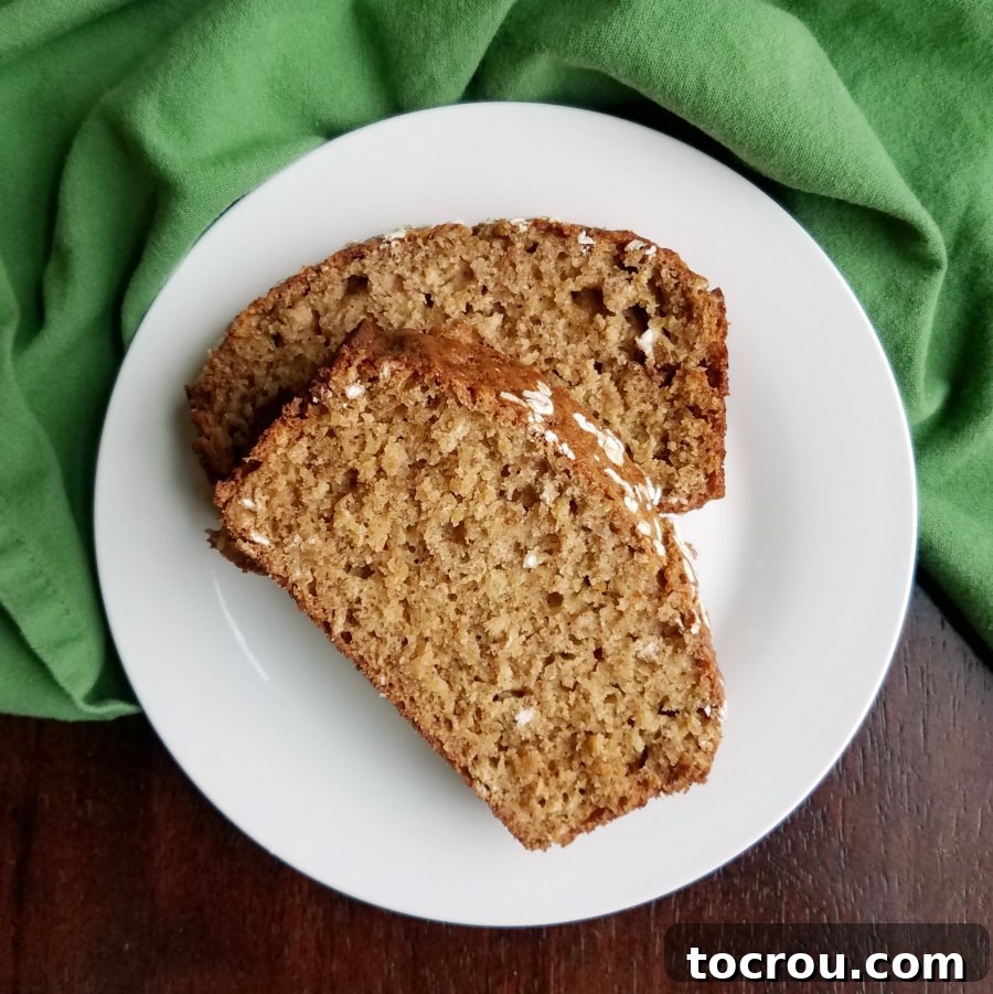 Multiple delicious slices of applesauce oatmeal quick bread elegantly arranged on a white plate, showcasing its soft texture and inviting golden hue.