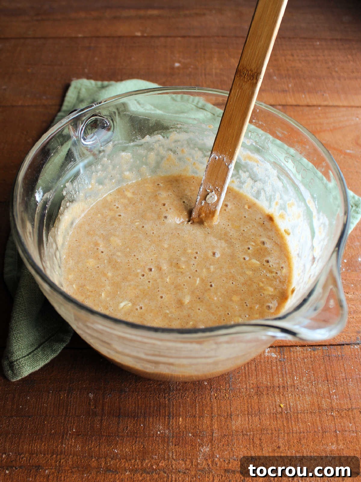 A large batter bowl brimming with the luscious, golden applesauce oatmeal quick bread batter, perfectly mixed and ready for the next step in the baking process.
