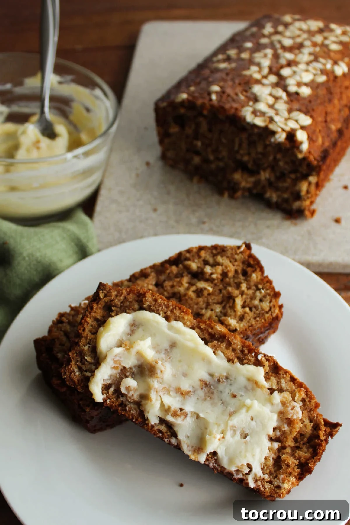 A single, inviting slice of applesauce quick bread, generously topped with a creamy layer of vanilla honey butter, poised for a delicious bite.